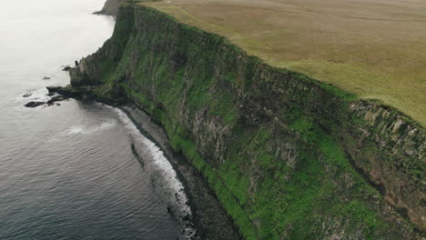 Low-flight-along-sheer,-rugged-cliff-of-Grimsey-Island,-Iceland,-Arctic-Circle
