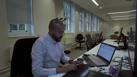 Un-Hombre-Asiático-Sentado-Y-Trabajando-En-Una-Computadora-O-Computadora-Portátil-En-El-Trabajo-En-La-Oficina-Tradicional