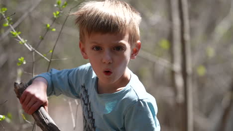 Little-boy-playing-with-a-stick-outdoors-in-the-forest,-slow-motion