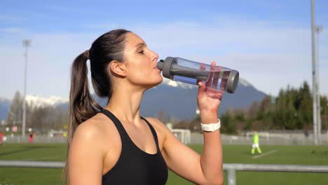 Attraktive-Sportliche-Frau-Trinkt-Wasser-Nach-Dem-Mittleren-Schuss