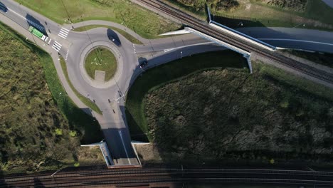 Traffic-circle-on-a-paved-road-recorded-from-a-drone-on-a-sunny-day-along-with-the-train-tracks