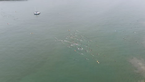 Aerial-view-of-unrecognizable-people-swimming-and-competing-in-a-triathlon,-flying-over-outdoor-competition
