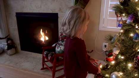 Entzückendes-Dreijähriges-Mädchen,-Das-Ornamente-Auf-Dem-Weihnachtsbaum-Am-Kamin-Betrachtet