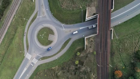 Traffic-circle-on-a-paved-road-recorded-from-a-drone-on-a-sunny-day-along-with-the-train-tracks