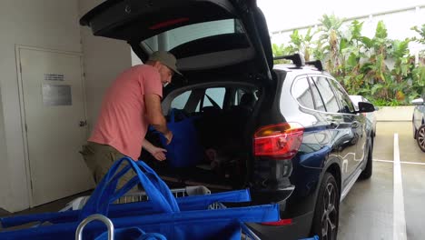 A-mature-man-unpacking-a-shopping-trolley-and-loading-the-groceries-into-the-back-of-a-car