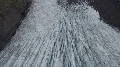 Reverse-flyover-above-deep-crevasses-in-large-Iceland-glacier,-dirty-with-silt
