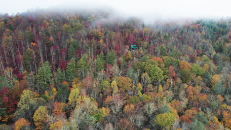 Drone-shot-of-fall-mountain-colors-in-the-Great-Smokey-Mountains-North-Carolina,-with-mountain-cabin-in-the-forest