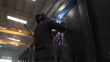 slow-motion-of-Indian-professional-welder-technician-working-with-mask-for-protection-from-fire-sparks-in-a-metal-iron-steel-truck-trailer-production,-Asia-manpower