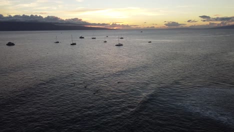 Drohnenaufnahme-Des-Sonnenuntergangs-An-Einem-Hawaiianischen-Strand-Mit-Booten-Und-Surfern