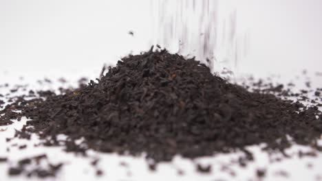 Black-Tea-Granules-Falling-On-Heap-Isolated-On-White-Background---close-up,-slow-motion