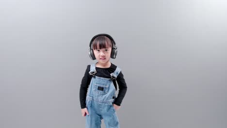 Cute-Asian-girl-wearing-headphones-enjoy-listening-to-music-and-dancing-happily-in-studio
