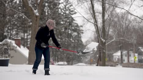 Woman-shovels-snow-in-a-suburban-neighborhood,-slow-motion