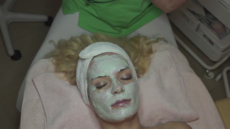 Frau-Mit-Gesichtsmaske-Zur-Hautpflege-Im-Spa-Salon,-Dermatologie-Und-Anti-Aging-Konzept,-Hochwinkelansicht