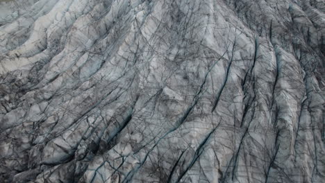 Flyover-above-Iceland-glacier,-with-cracks-and-crevasses-visible-in-ice