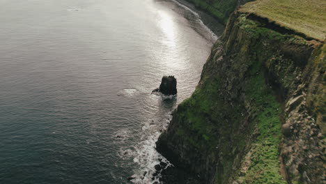 Aerial-zoom-towards-ocean-surface-along-cliffs-of-Grimsey-Island,-Arctic-Circle