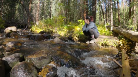 Female-hiker-sitting-next-to-Colorado-mountain-stream-thinking,-static