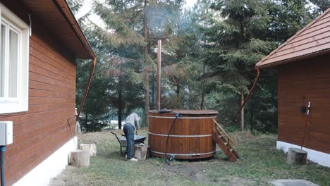Man-Putting-Wood-Into-Furnace-Of-A-Traditional-Wooden-Hot-Tub-Outdoor