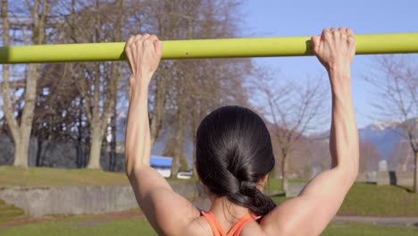 Young-woman-doing-pull-ups-exercising-outdoors