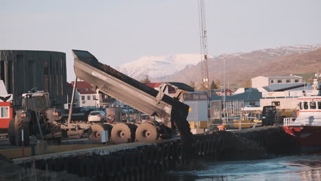 Dump-truck-dumping-load-of-dirt-into-fjord-in-Akureyri-Iceland
