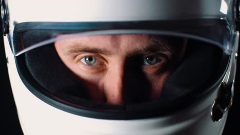 Man-with-strong-blue-eyes-looking-into-the-camera-and-closing-the-helmet-visor-in-4k-slow-motion-close-up-of-face