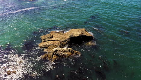 Orbiting-aerial-view-of-a-large-rock-in-the-ocean