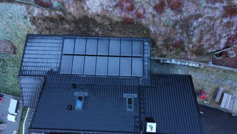 Frozen-solar-panels-with-zero-electricity-production-during-dark-winter-season---Upward-moving-top-down-aerial-of-private-home-in-Norway