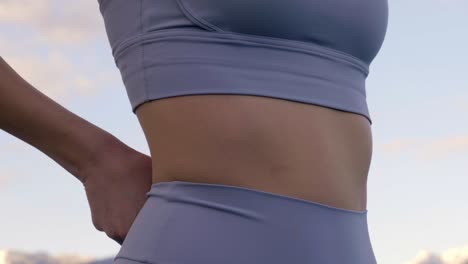 Woman-adjusting-sports-leggings-around-stomach,-Slow-Motion-Closeup