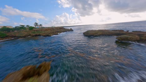Fpv-aerial-flight-along-rocky-coastline-and-clear-blue-water-of-Caribbean-Sea---Ascending-shot-with-panorama-shot-over-Green-growing-countryside-of-Dominican-Republic