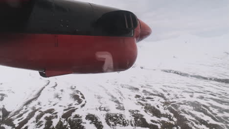 Close-up-of-spinning-propeller-on-small-plane-flying-over-snow-capped-mountains,-Iceland