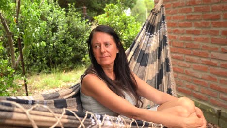 Caucasian-Woman-In-Her-50's-Chilling-On-A-Swinging-Hammock-Outside-The-House