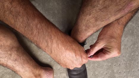 An-impatient-older-caucasian-man-struggles-to-tie-his-shoelaces