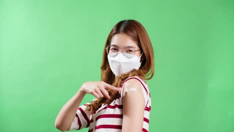 The-portrait-of-an-Asian-woman-with-eyeglasses-is-smiling-on-a-mask-being-positive-emotions-and-Cheerful-vaccinated-showing-arm-with-medical-patch-and-laughs-plaster-on-her-shoulder