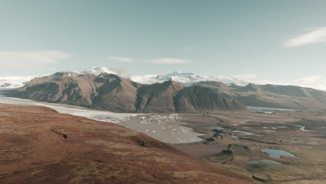 Revelación-Aérea-Del-Valle-Glacial-En-Islandia-Y-Icebergs-Flotando-En-Un-Estanque-De-Sedimentos