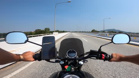 Sicht-Kaukasier,-Der-Ein-Yamaha-Motorrad-Auf-Einer-Leeren-Autobahn-In-Thailand-Fährt,-Während-Lastwagen-An-Einem-Sonnigen-Tag-Mit-Einem-Auf-Dem-Fahrrad-Montierten-IPhone-In-Die-Entgegengesetzte-Richtung-Fahren