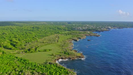 Aerial-flight-along-rural-coastline-of-Boca-de-Yuma-during-sunny-day-and-blue-sky---Aerial-view-of-green-forest-landscape-and-blue-Caribbean-Sea