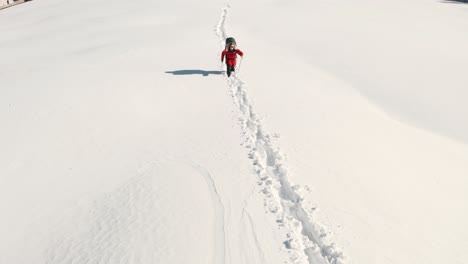 Niedrige-Luftaufnahme-In-Richtung-Abenteuerlustiger-Mann,-Der-Mit-Großer-Trekkingtasche-Durch-Tiefen-Schnee-Geht