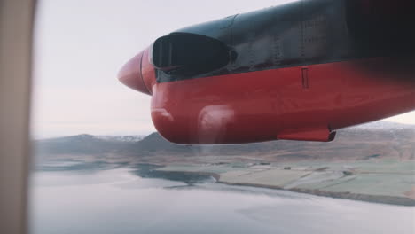 View-out-window-of-small-plane-propeller-as-plane-flies-over-Iceland-fjord