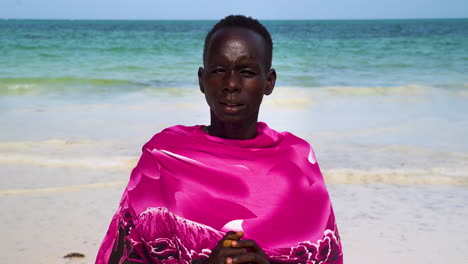 Indigenous-african-man-in-pink-clothing-on-white-sand-beach,-close-up