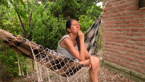 Caucasian-Woman-Sitting-And-Relaxing-On-A-Hammock-Outside-The-House