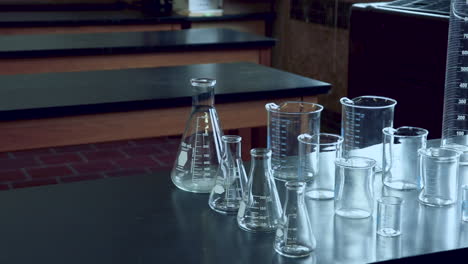 Panning-across-black-lab-bench-with-a-variety-of-chemical-glassware-in-high-school-chemistry-lab