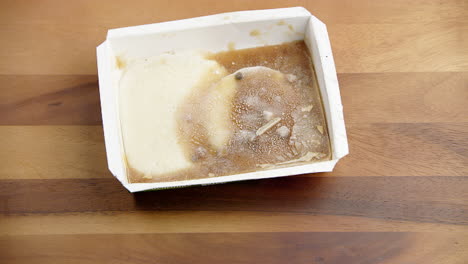 Frozen-plain-snack-food-in-a-container,-melting-at-room-temperature-on-the-dining-table