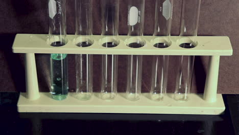 Close-up-of-blue-copper-sulfate-solution-being-added-to-a-test-tube-in-a-rack