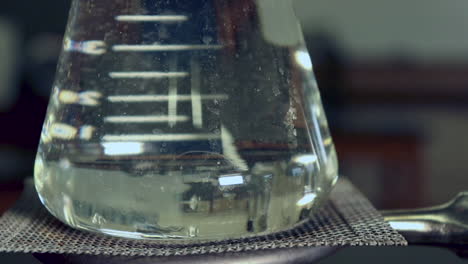 Close-up-of-water-beginning-to-boil-in-the-bottom-of-an-erlenmeyer-flask