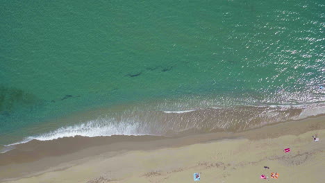 Static-aerial-shot-of-the-beach-shore-and-the-turquoise-ocean-in-Marbella,-Spain