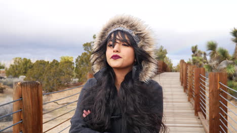 Beautiful-young-woman-looking-serious-on-a-bridge-in-the-desert-in-stormy-bad-weather-under-cloudy-sky-SLOW-MOTION