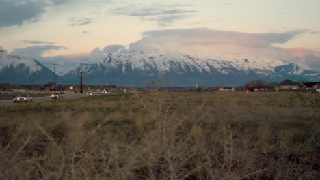 View-of-the-snow-capped-mountains-in-early-morning-or-evening-from-between-two-highway-roads---sliding-shot