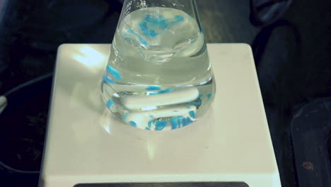 Cierre-De-Cristales-Azules-De-Sulfato-De-Cobre-Pentahidratado-Que-Se-Agregan-Al-Matraz-Erlenmeyer-En-Agitador-Magnético