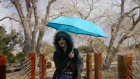 Eine-Schöne-Frau,-Die-Einen-Blauen-Regenschirm-öffnet-Und-Während-Eines-Regensturms-Glücklich-Lächelt,-Um-Sich-Vor-Schlechtem-Wetter-In-Zeitlupe-Zu-Schützen