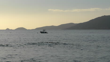 Ruhige-Ozeanszene,-Verankertes-Boot,-Hintergrundberge-Bei-Sonnenuntergang