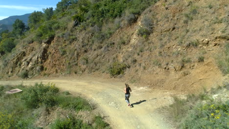 Aerial-footage-of-a-blonde-woman-jogging-down-the-mountain-in-Marbella,-Spain
